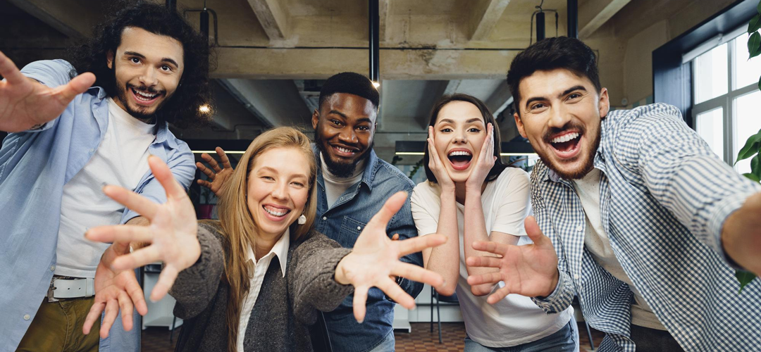 Cinq salariés joyeux en selfie de groupe dans un bureau, illustrant la fidélisation grâce aux avantages sociaux en entreprise